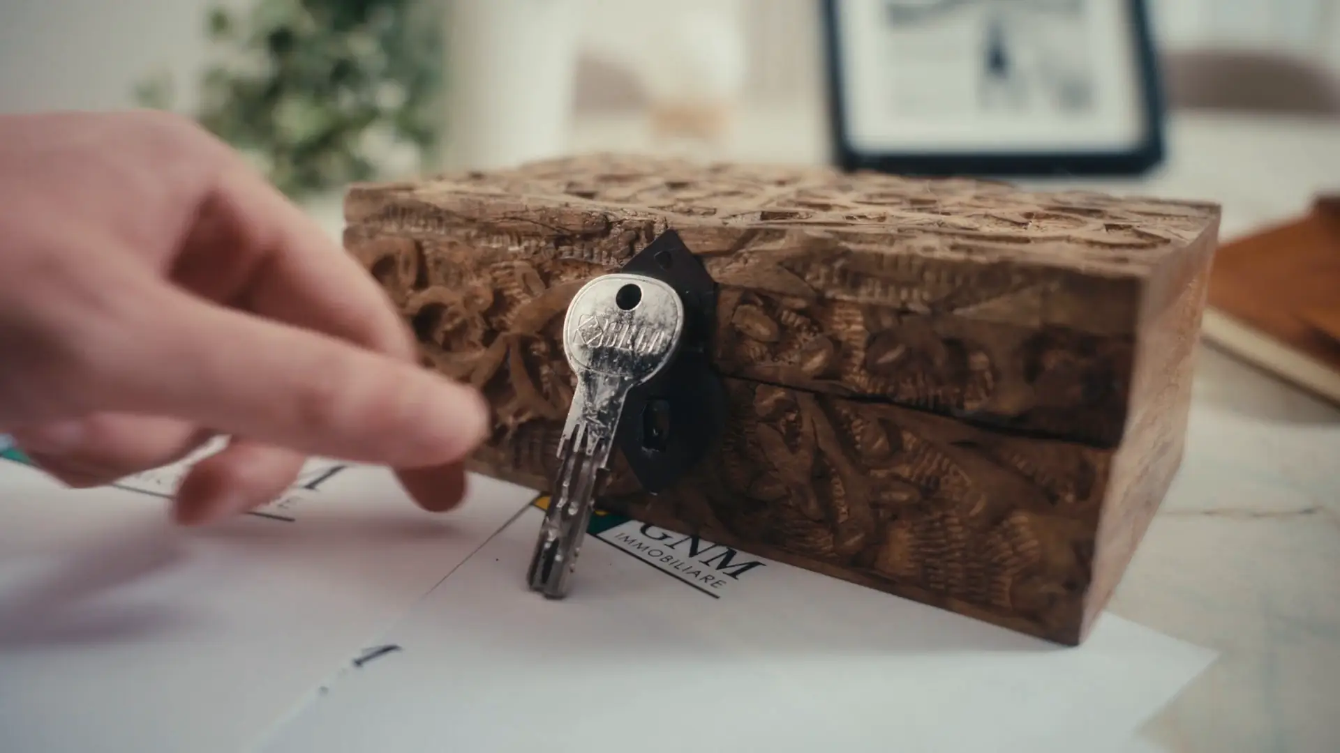 Una chiave e una scatola di legno sui documenti, dallo spot Gnm Immobiliare