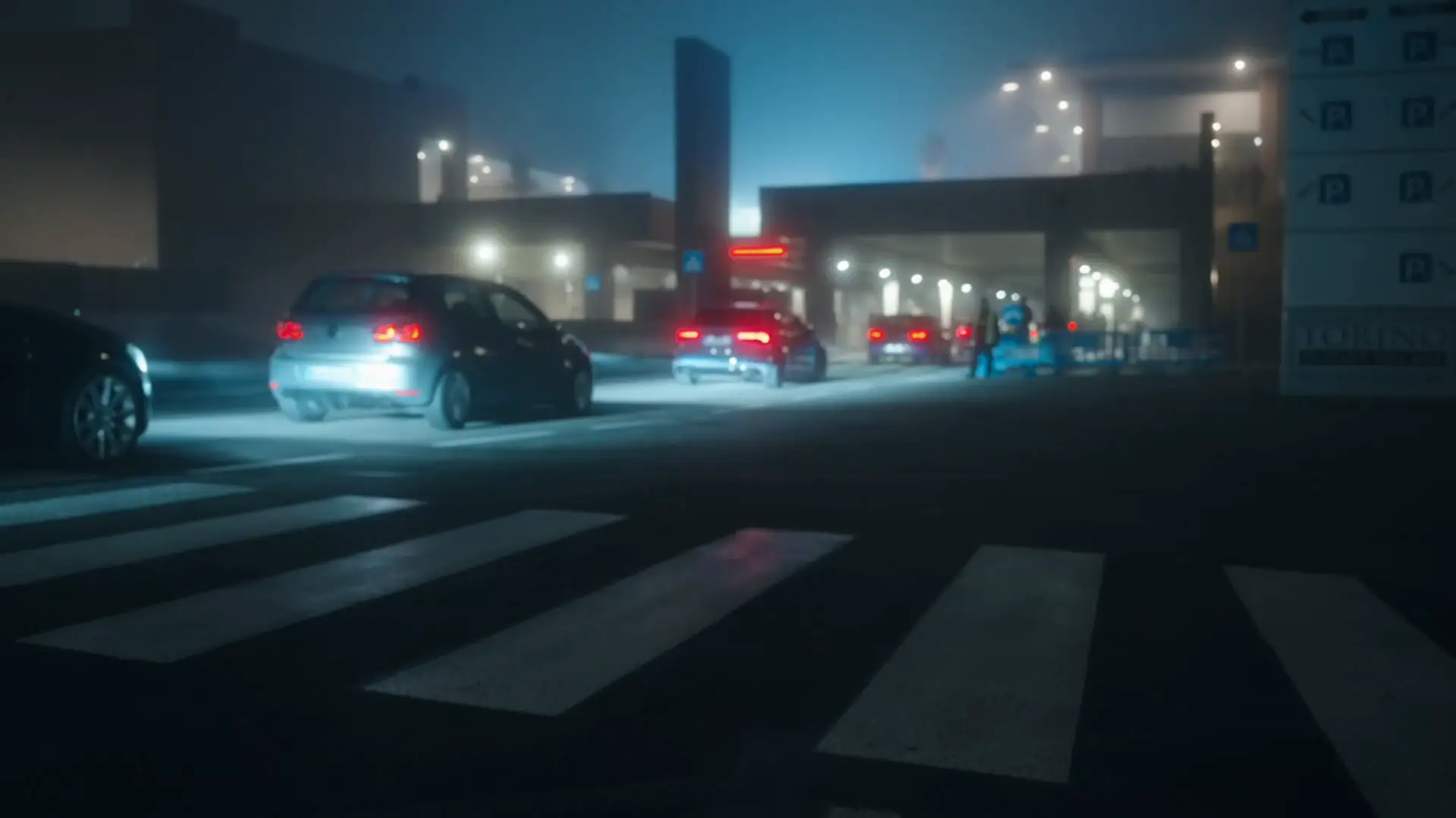 Hardcore Drivers: auto con i fari accesi nella nebbia, di sera, davanti al Torino Outlet Village